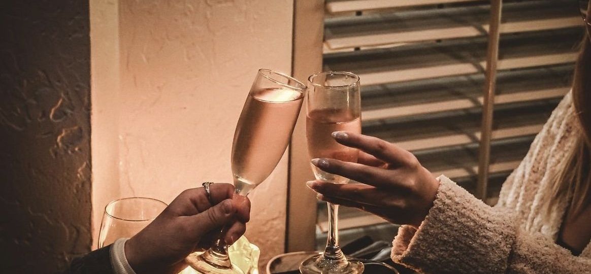 couple seated at restaurant cheering with champagne glasses